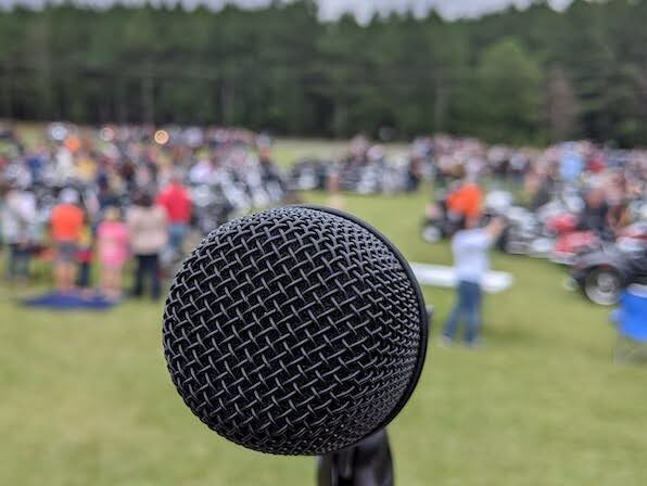 a microphone from close up at an outdoor festival. the microphone is in focus, with the background blurred out. 