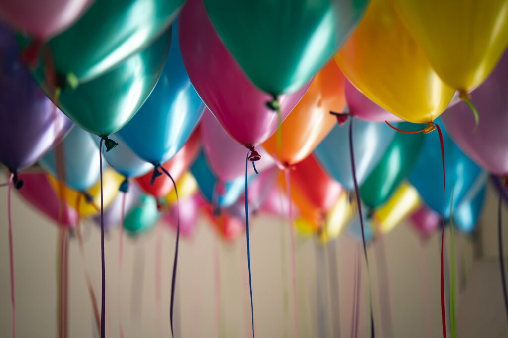 multi-colored helium-filled birthday balloons with strings hanging down