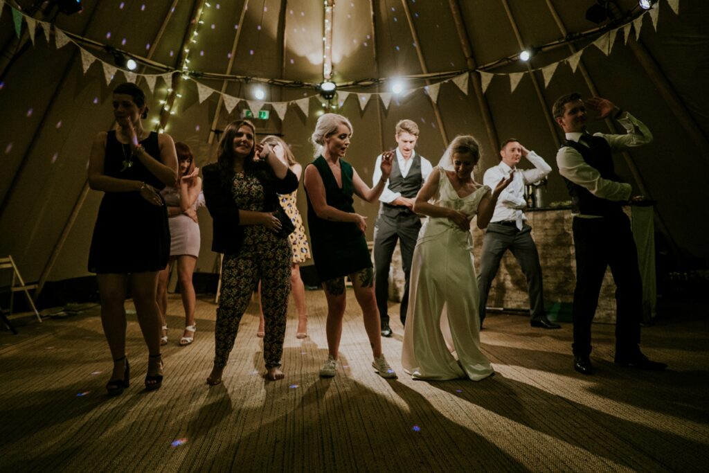 a wedding party with dancers on the floor smiling and doing a line dance